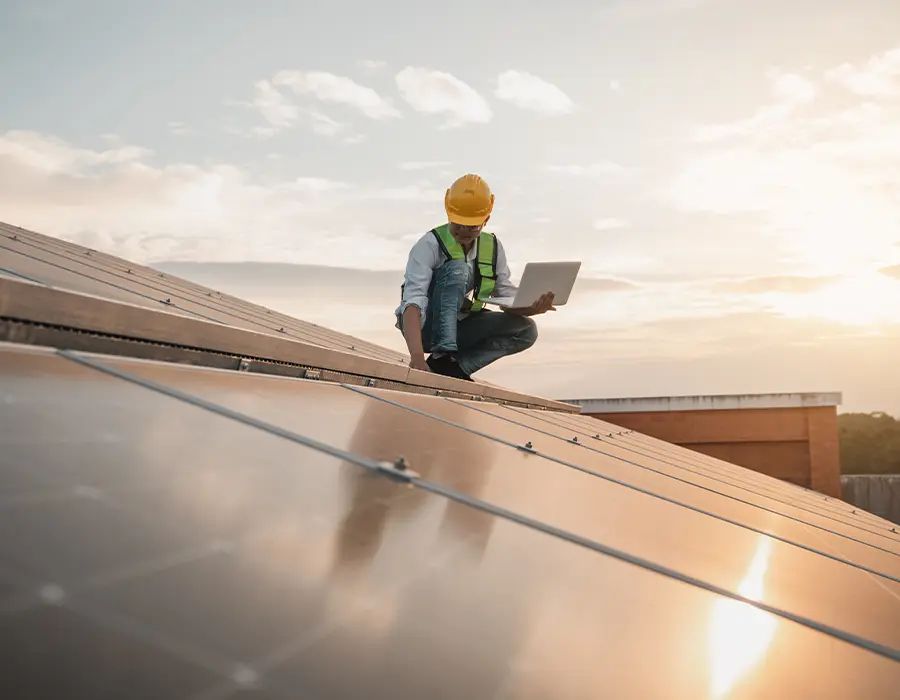 Un homme sur un toit en train de vérifier les panneaux photovoltaïques