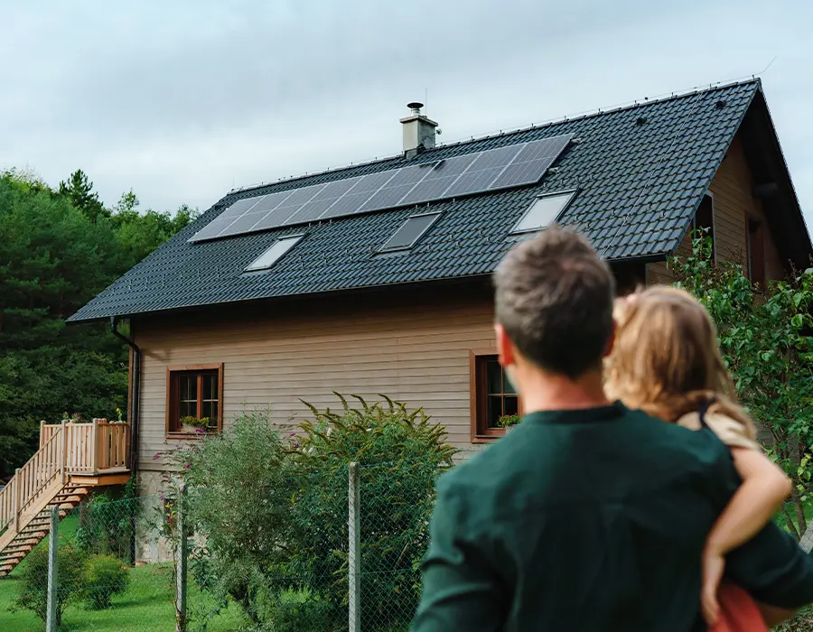 Un père et sa fille regardant leurs panneaux photovoltaïques sur le toit de leur maison